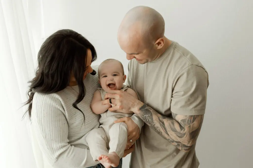 Baby Easton being held by his parents, both smiling, during a 6-month milestone photography session