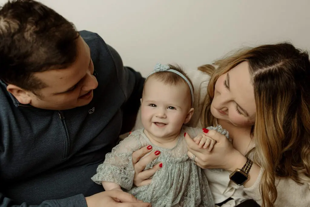 Baby Eyla smiling while sitting with her parents during a family photography session