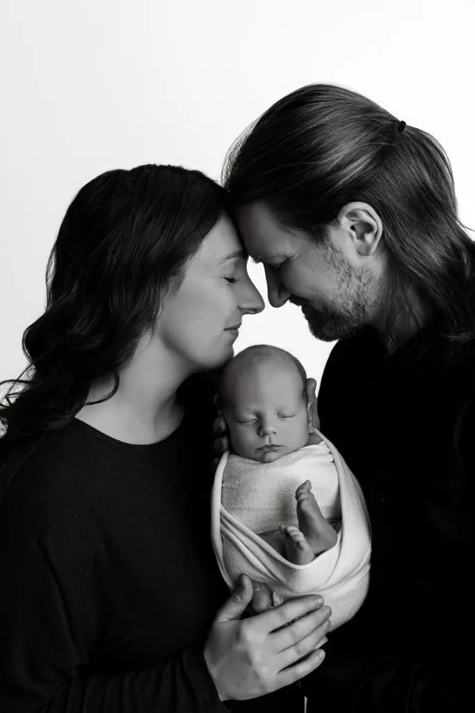 A timeless black-and-white family portrait with mom, dad, and their newborn baby. Taken during a newborn photography session in Cedar Falls, Iowa, for families in Cedar Falls, Waterloo, and Waverly