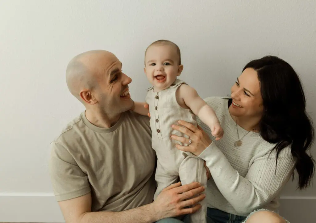 A Marine family smiling and holding their happy 6-month-old baby, Easton, during a milestone session