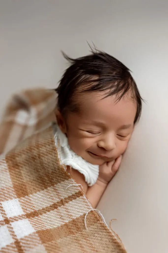 Newborn baby Isaiah peacefully posed in a crescent moon prop with a starry background, captured during a Cedar Falls, Iowa photography session