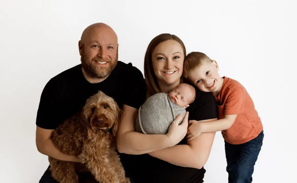 Family photo with newborn baby Hudson, older brother Camdyn, and their goldendoodle during a newborn photography session in Cedar Falls, Iowa.