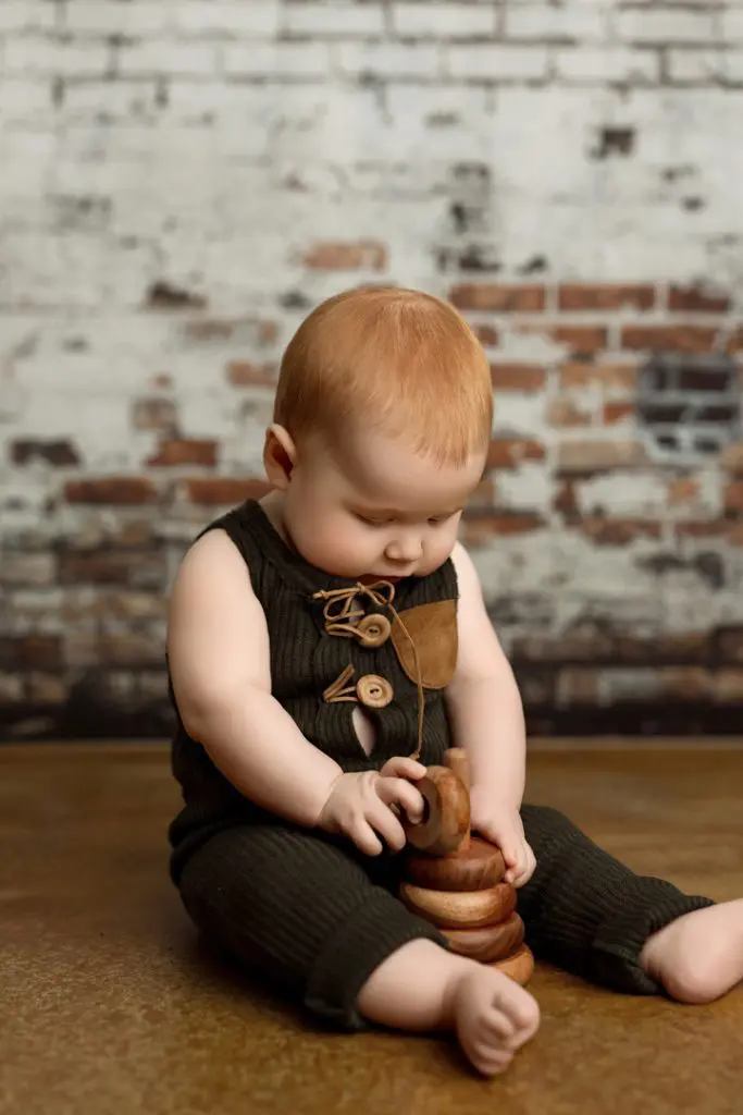 Baby boy Colter playing with wooden blocks during his 6-month milestone photography session.
