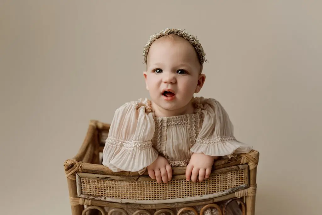 Smiling baby girl in a rustic basket during milestone photography session near Hudson, IA.