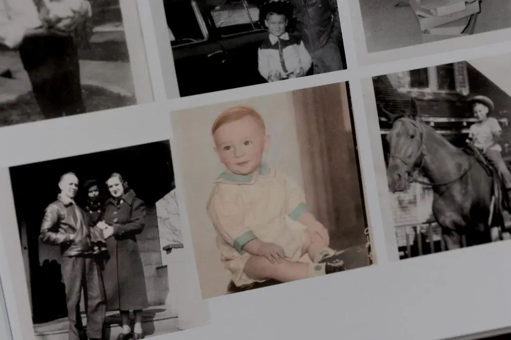 Vintage photo of baby grandfather in a cream and teal romper sitting on a bench.