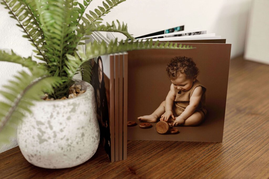 Photo album displayed on a wooden table, featuring a baby portrait and modern design, available in Cedar Falls, Iowa. Serving families in Cedar Falls, Independence, New Hartford, and Traer.