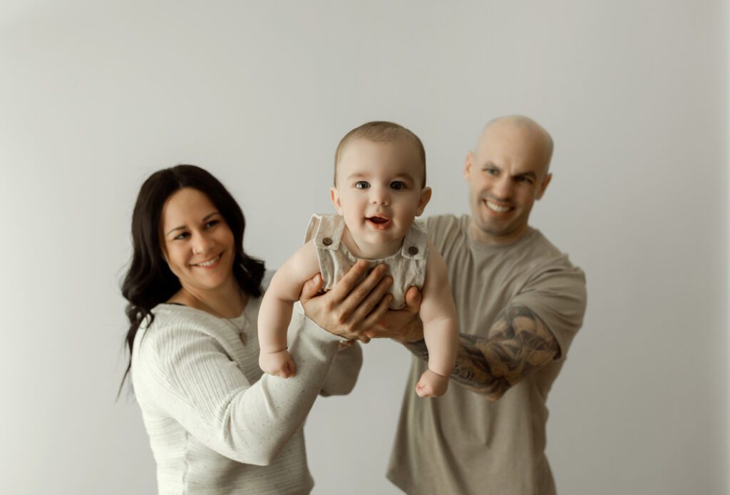 Baby Easton being held by his parents, both smiling, during a 6-month milestone photography session