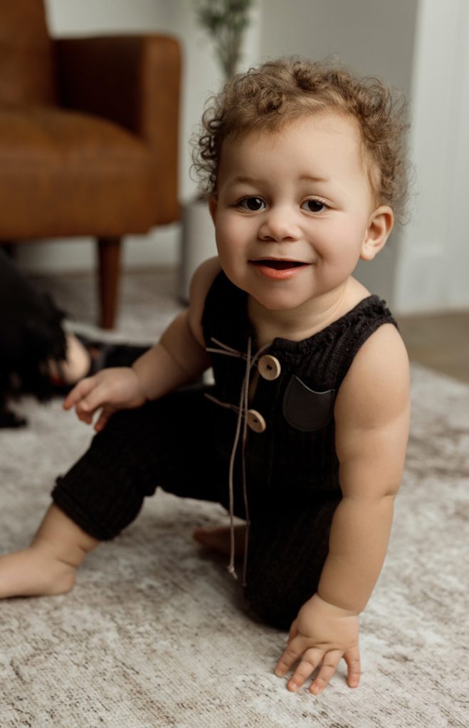 Smiling baby crawling on a cozy rug during a newborn photography session in Cedar Falls, Iowa, capturing natural and playful moments.