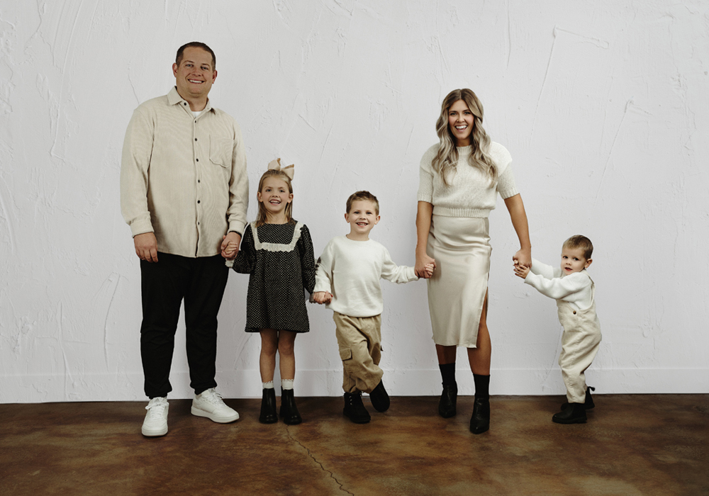 Family holding hands and laughing in photography studio near Denver, IA.