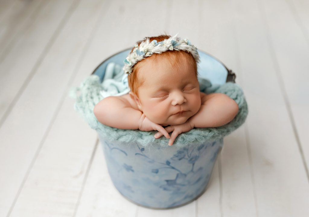 Newborn posed in blue floral bucket, Denver Iowa professional newborn photography.