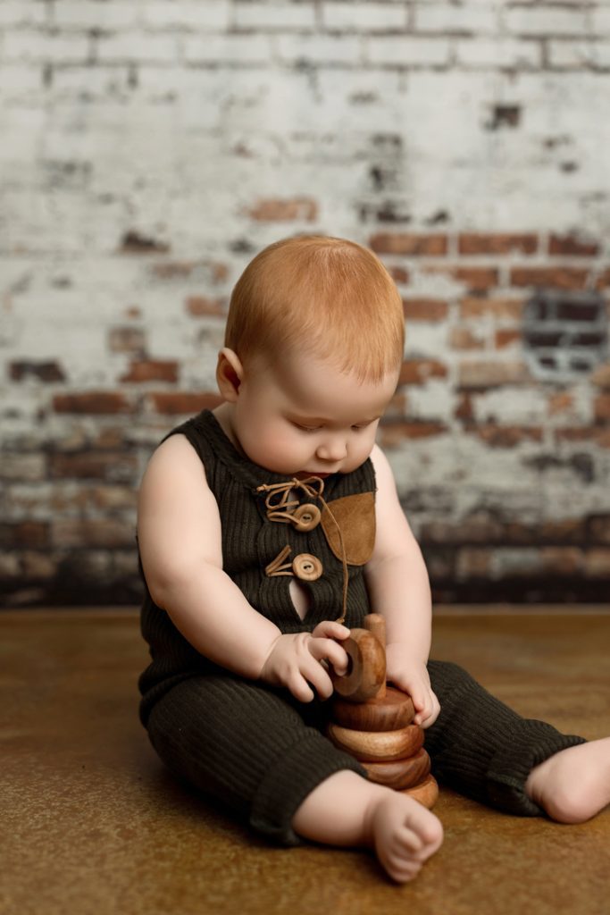 Baby boy Colter playing with wooden blocks during his 6-month milestone photography session.