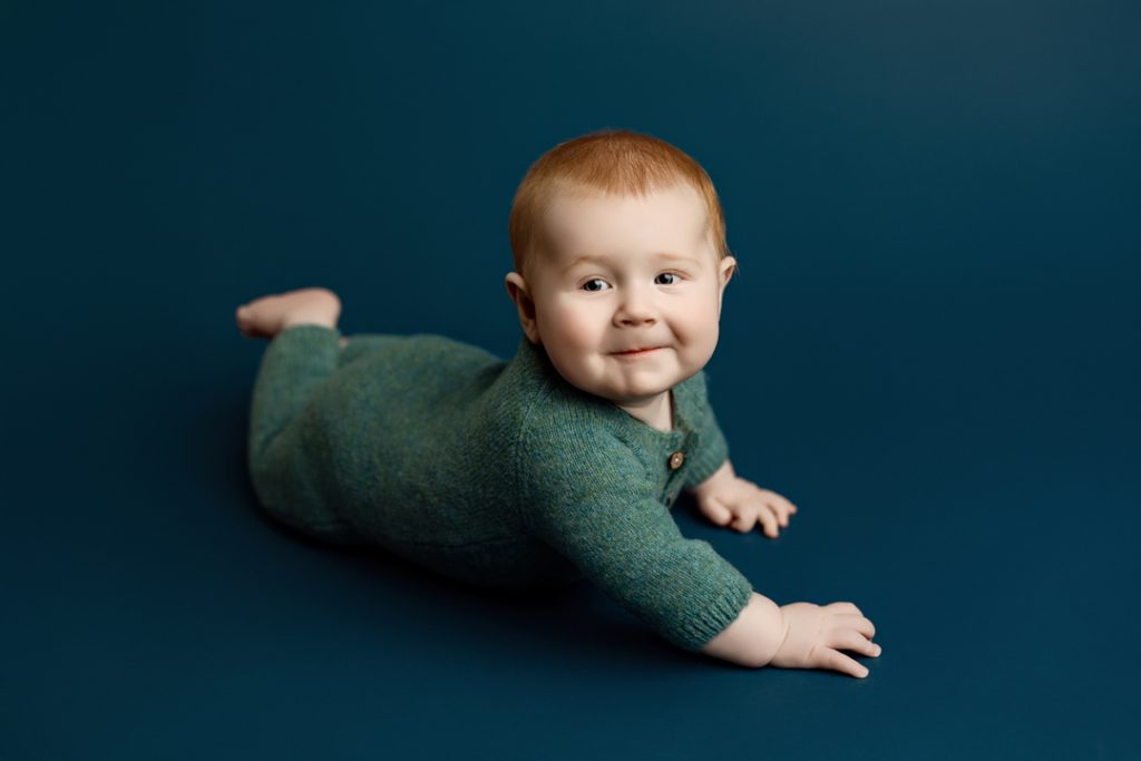 Baby boy Colter on his tummy smiling during six-month milestone photos.