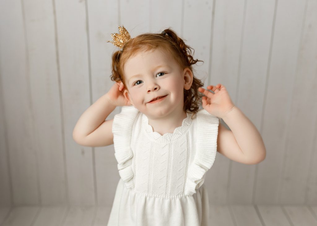 Toddler girl wearing crown, sibling portrait during newborn session in Cedar Valley, Iowa.