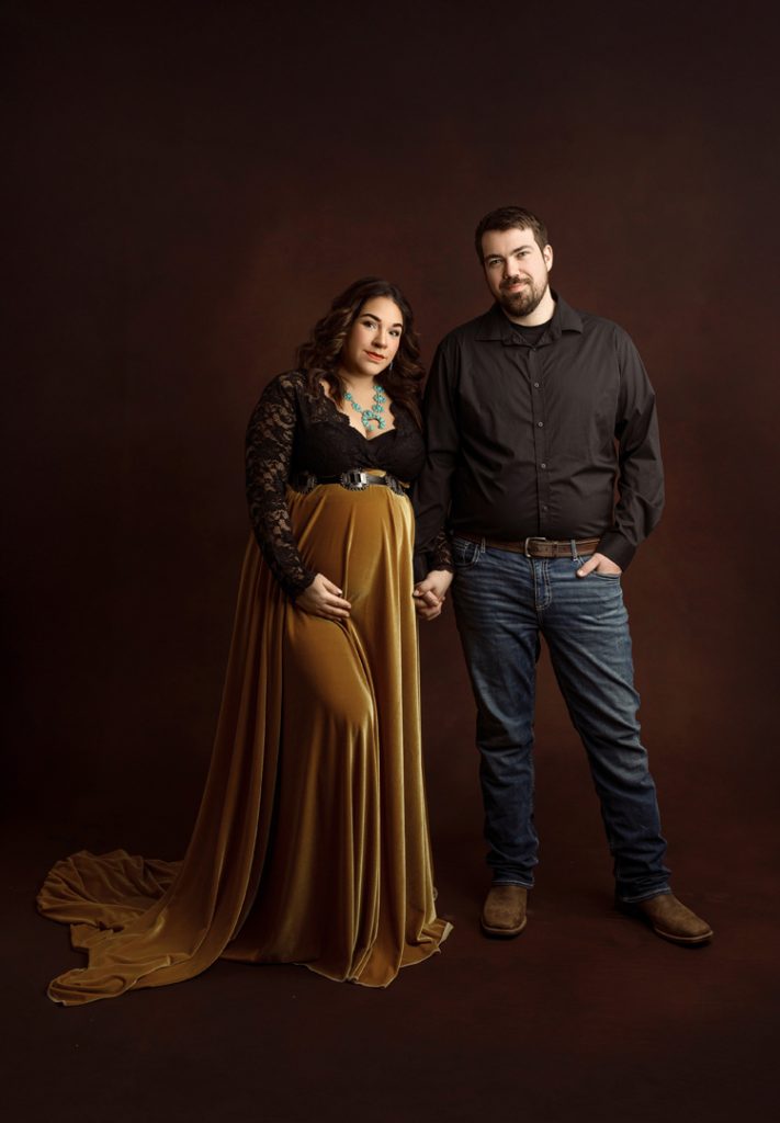 Couple holding hands during their western-themed maternity session near Hudson, Iowa.
