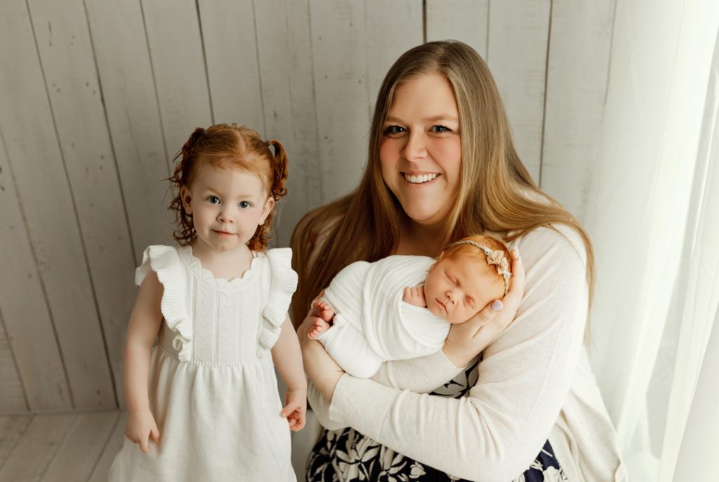 Family portrait with mom and two daughters during newborn photo session in Cedar Falls, Iowa.