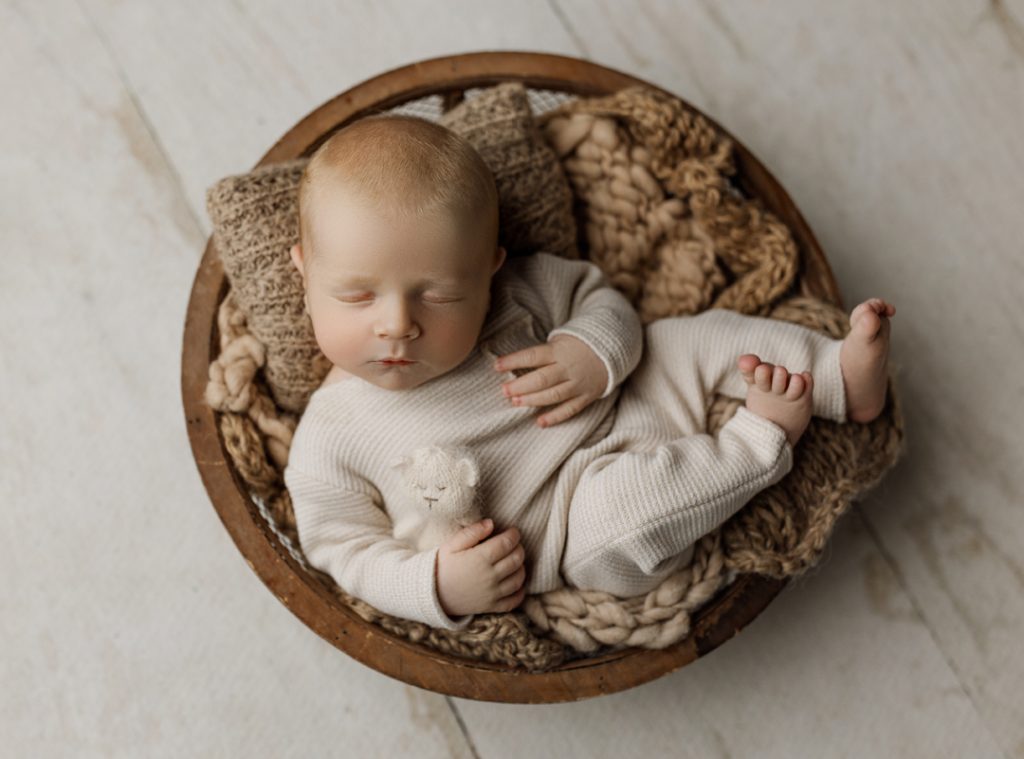 Newborn milestone session with cream romper at Cedar Falls photography studio.