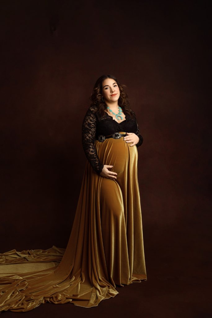 Glamorous western-themed maternity portrait featuring a custom-made golden velvet skirt in Waverly, Iowa studio.