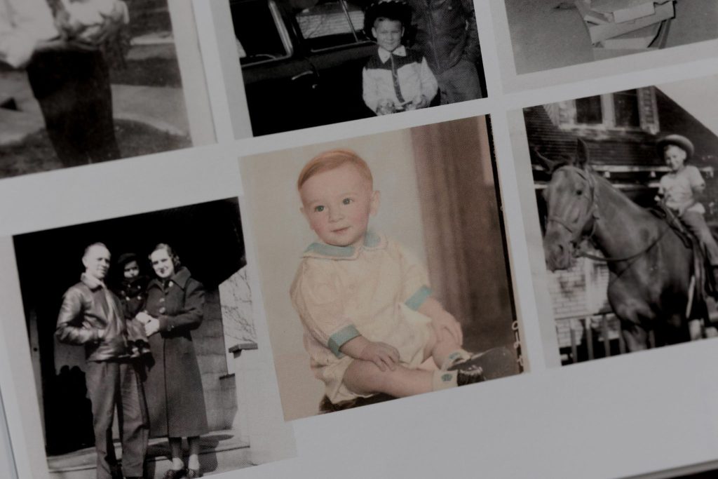 Vintage photo of baby grandfather in a cream and teal romper sitting on a bench.