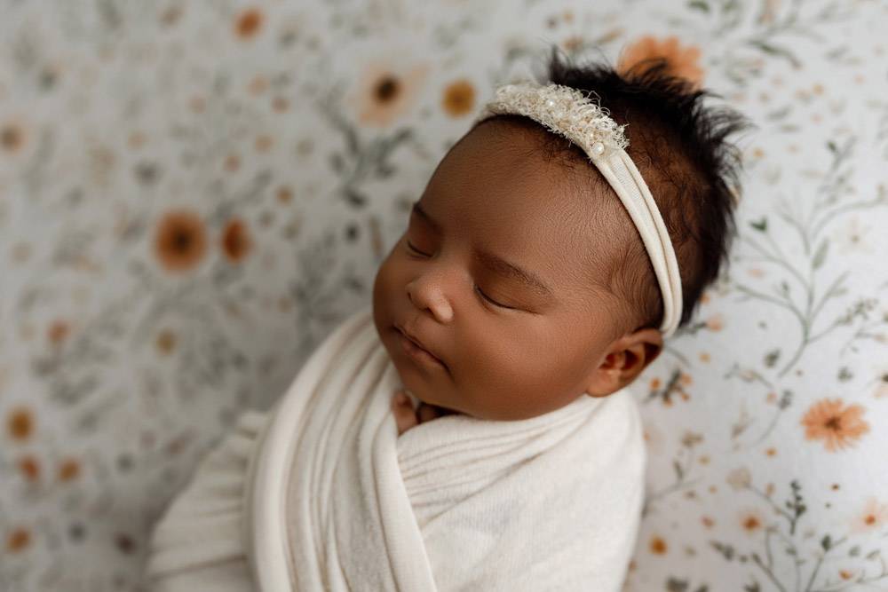 Close-up of Reina peacefully asleep with floral headband on a custom prop backdrop in Cedar Falls