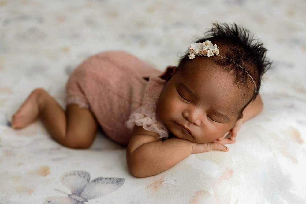Baby Reina peacefully sleeping on a butterfly-themed backdrop during her newborn session in Cedar Falls, Iowa