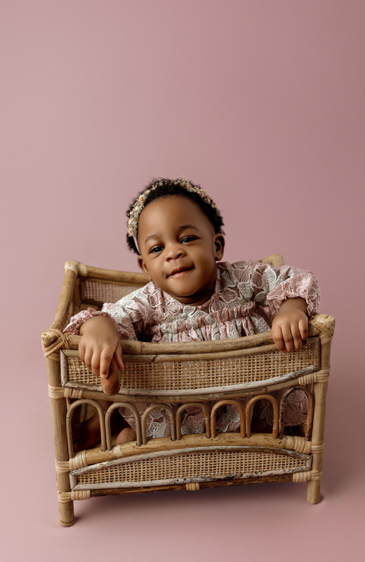 First birthday milestone photo of baby Amy in pink lace dress taken in Cedar Falls Iowa.
