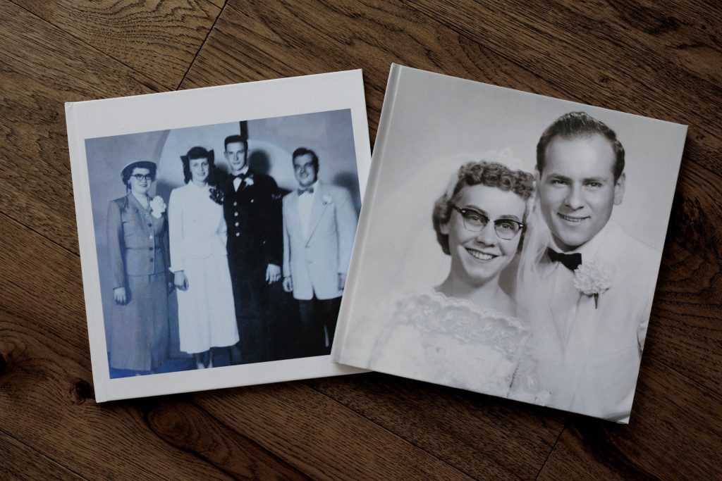 Vintage wedding photo album covers featuring grandparents on a wooden floor.